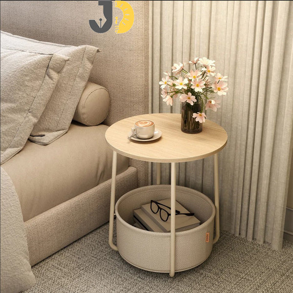 طاولة جانبية دائرية خشبية مع سلة تخزين قماشية بجانب السرير
Round wooden side table with fabric storage basket beside bed