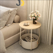طاولة جانبية دائرية خشبية مع سلة تخزين قماشية بجانب السرير
Round wooden side table with fabric storage basket beside bed